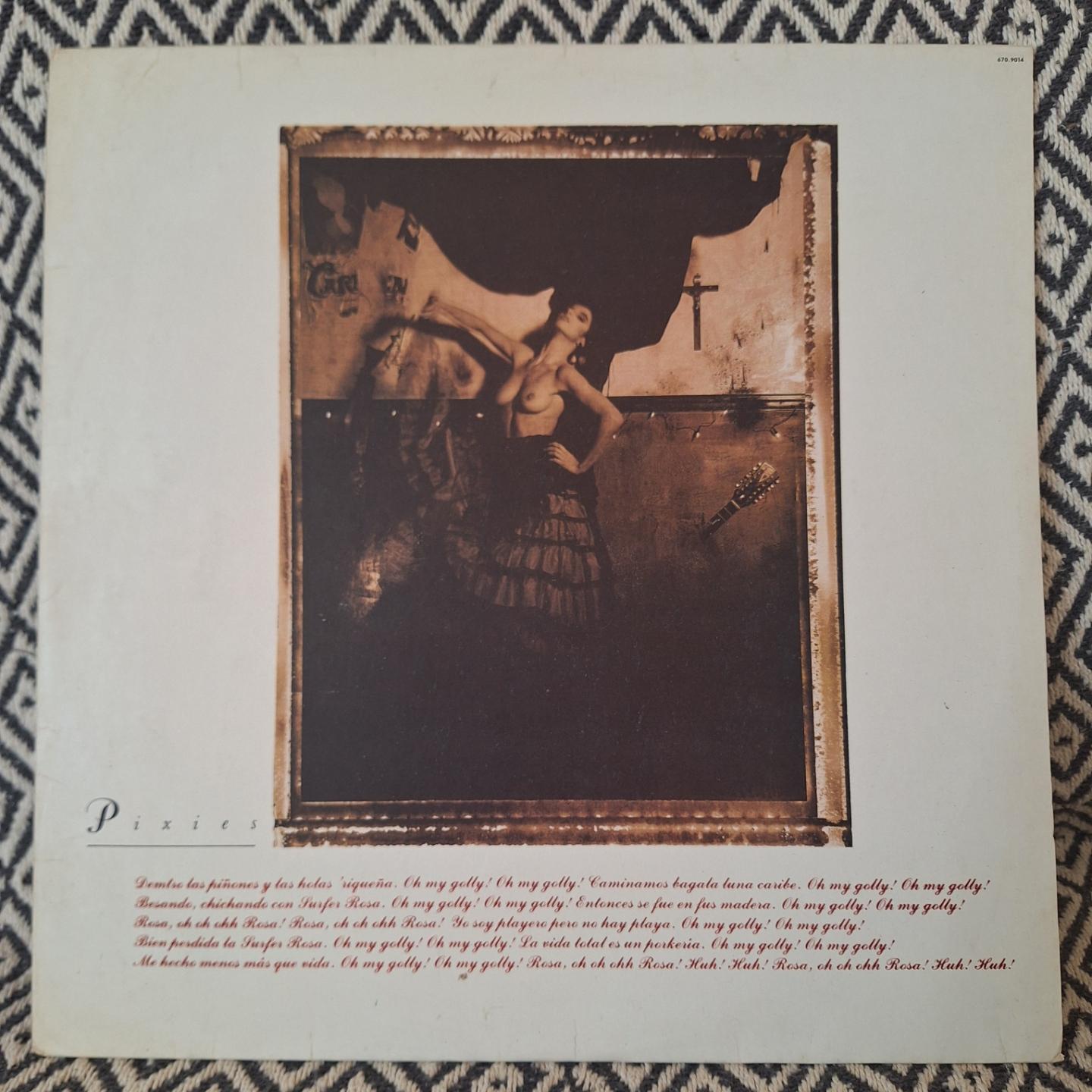 Capa do disco Surfer Rosa. A capa é branca e mostra uma foto sépia onde uma mulher de saia e nada na parte de cima posa com o peito a mostra em um cenário que parece uma casa abandonada.